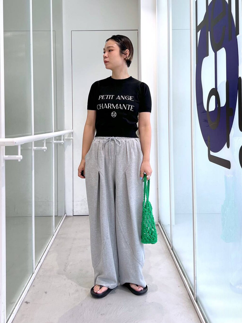 グレー系のスウェットパンツ、ブラック系のサンダル、グリーン系のトートバッグを着用したレディースの夏コーディネートの5枚目の写真