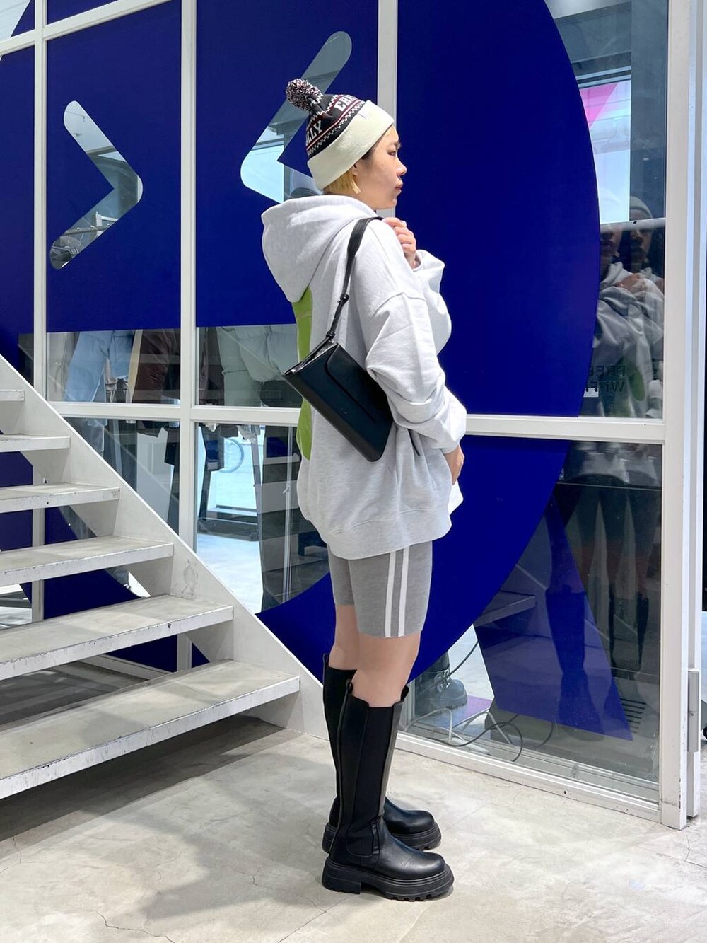 ブラック系のブーツ、ブラック系のショルダーバッグ、グレー系のパーカーを着用したレディースの秋コーディネートの5枚目の写真