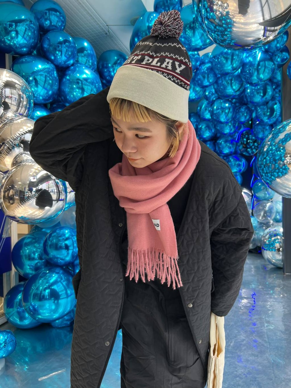 ベージュ系のトートバッグ、ピンク系のマフラー、グレー系のニットキャップ/ビーニーを着用したレディースの冬コーディネートの4枚目の写真