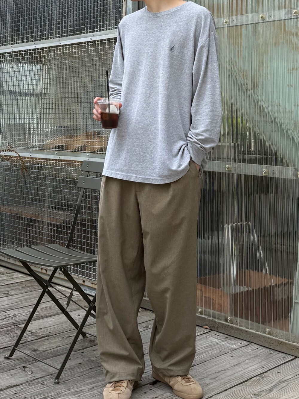 グリーン系のスラックス、グレー系のTシャツ/カットソー、ベージュ系のスニーカーを着用したメンズの春コーディネートの2枚目の写真