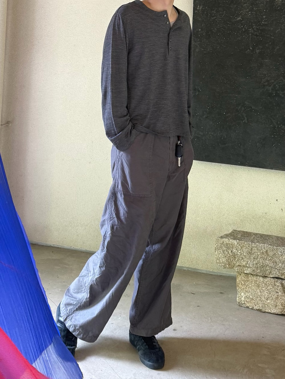 グレー系のトップス、ブラック系のカーゴパンツ、ブラック系のスニーカーを着用したメンズの春コーディネートの2枚目の写真