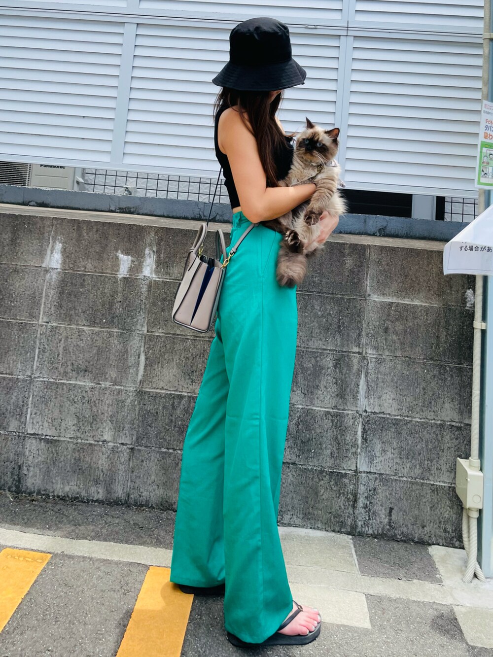 グレー系のショルダーバッグ、グリーン系のスラックス、ブラック系のタンクトップを着用したレディースの夏コーディネートの2枚目の写真