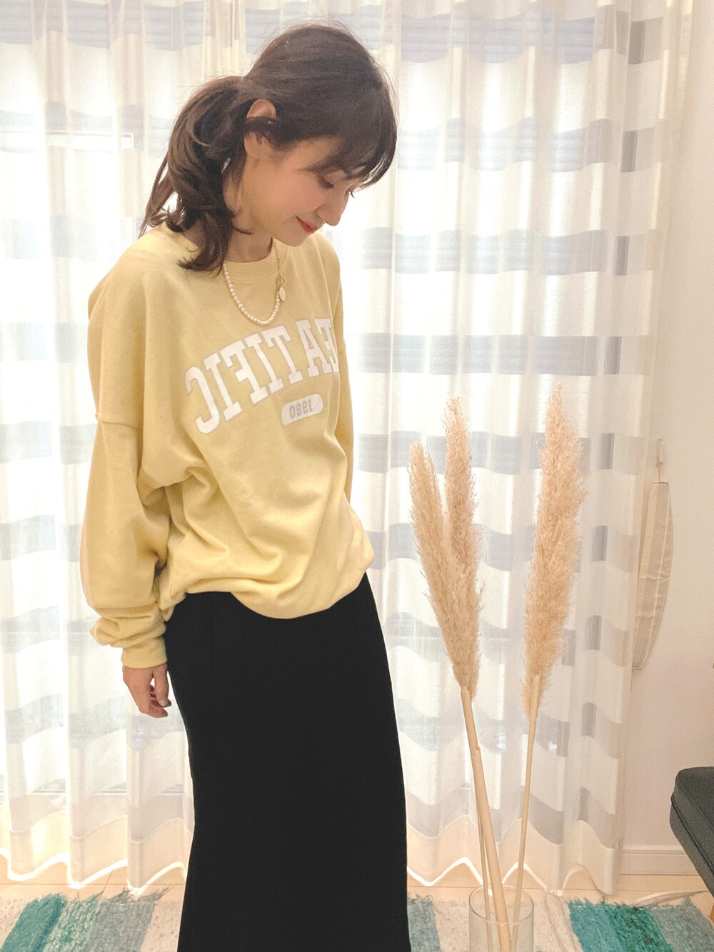 ブラック系のスカート、イエロー系のスウェット、ゴールド系のネックレスを着用したレディースの冬コーディネートの2枚目の写真