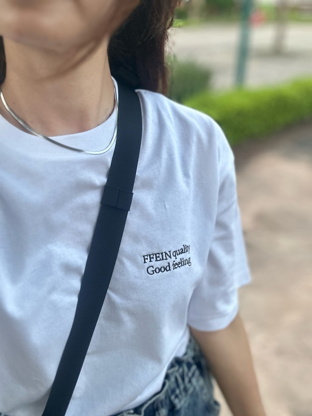 ホワイト系のTシャツ/カットソー、ブラック系のボディバッグ/ウエストポーチを着用したレディースの夏コーディネートの2枚目の写真