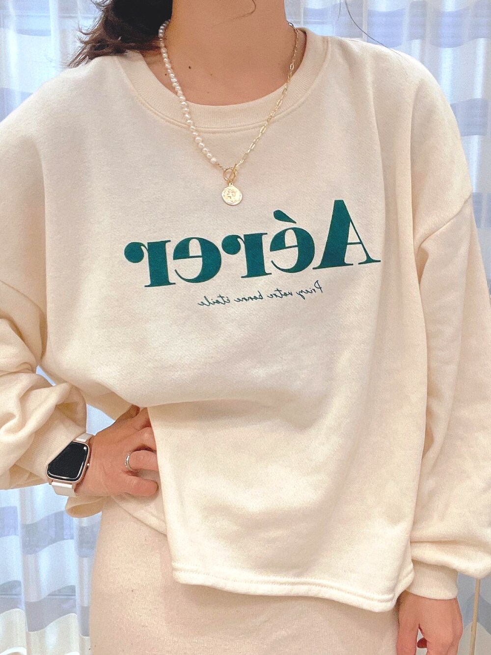 ベージュ系のスウェット、ホワイト系のスカート、ゴールド系のデジタル腕時計を着用したレディースの冬コーディネートの2枚目の写真