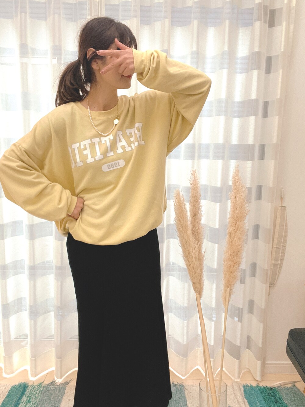 ブラック系のスカート、イエロー系のスウェット、ゴールド系のネックレスを着用したレディースの冬コーディネートの3枚目の写真