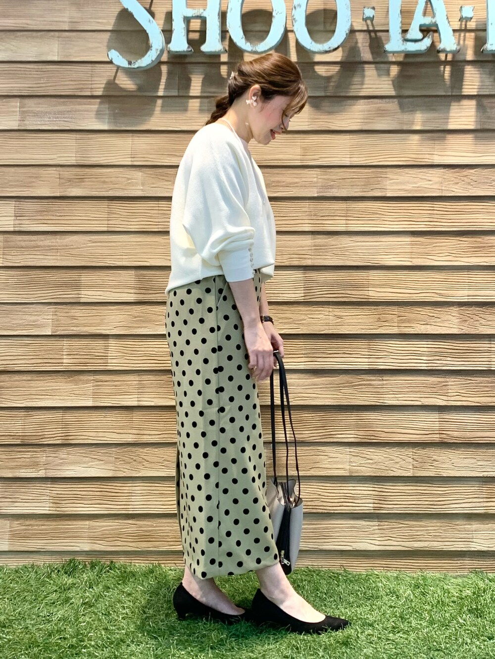 ホワイト系のニット/セーター、グリーン系のスカート、ブラック系のショルダーバッグを着用したレディースの春コーディネートの4枚目の写真