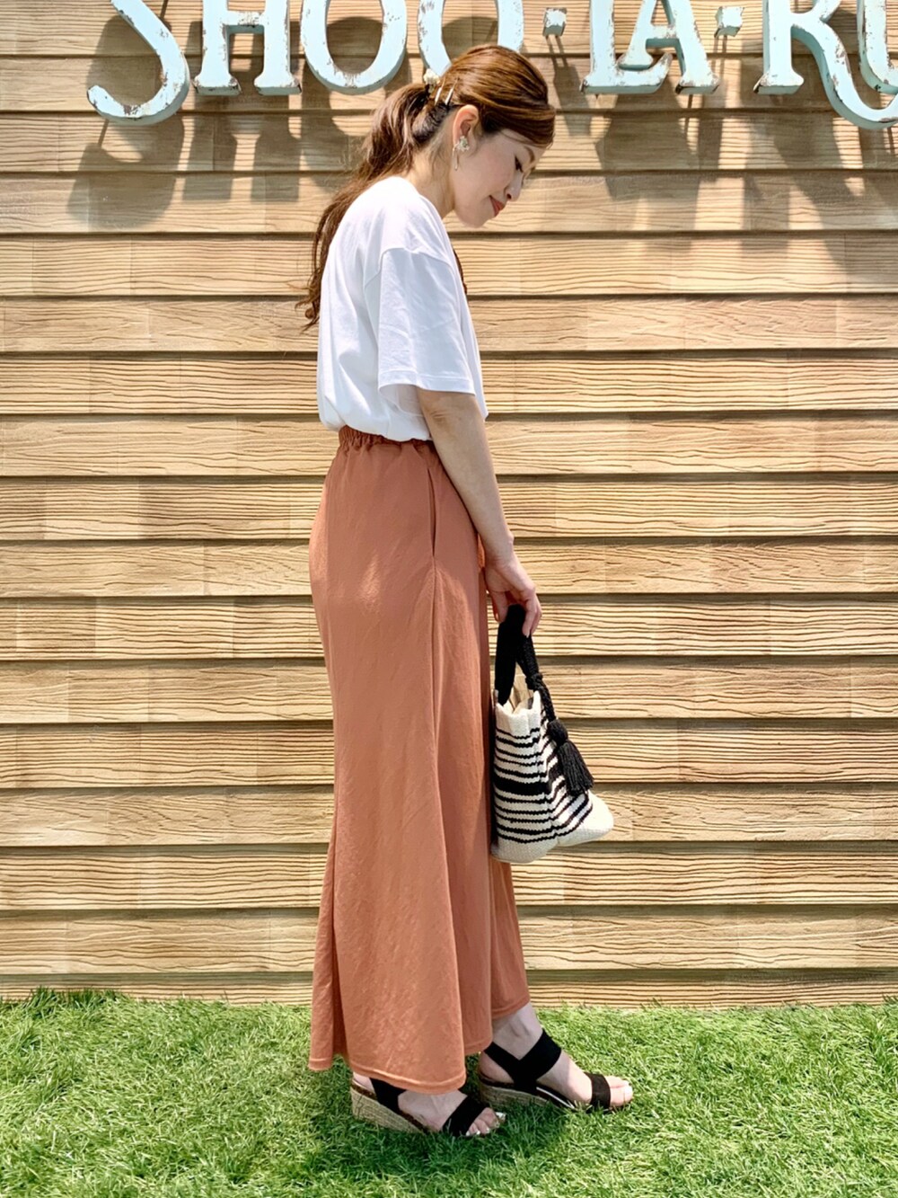 ホワイト系のTシャツ/カットソー、オレンジ系のスカート、ブラック系のトートバッグを着用したレディースの夏コーディネートの4枚目の写真