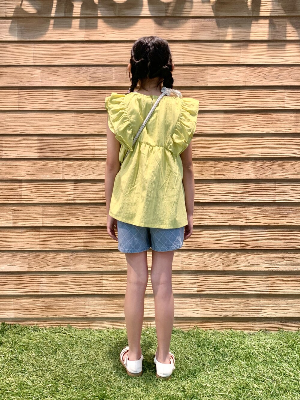 イエロー系のシャツ/ブラウス、ホワイト系のショルダーバッグ、ブルー系のデニムパンツを着用したキッズの夏コーディネートの5枚目の写真