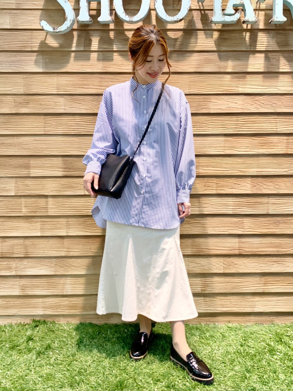 ブルー系のワンピース、ホワイト系のデニムスカート、ブラック系のショルダーバッグを着用したレディースの春コーディネートの2枚目の写真