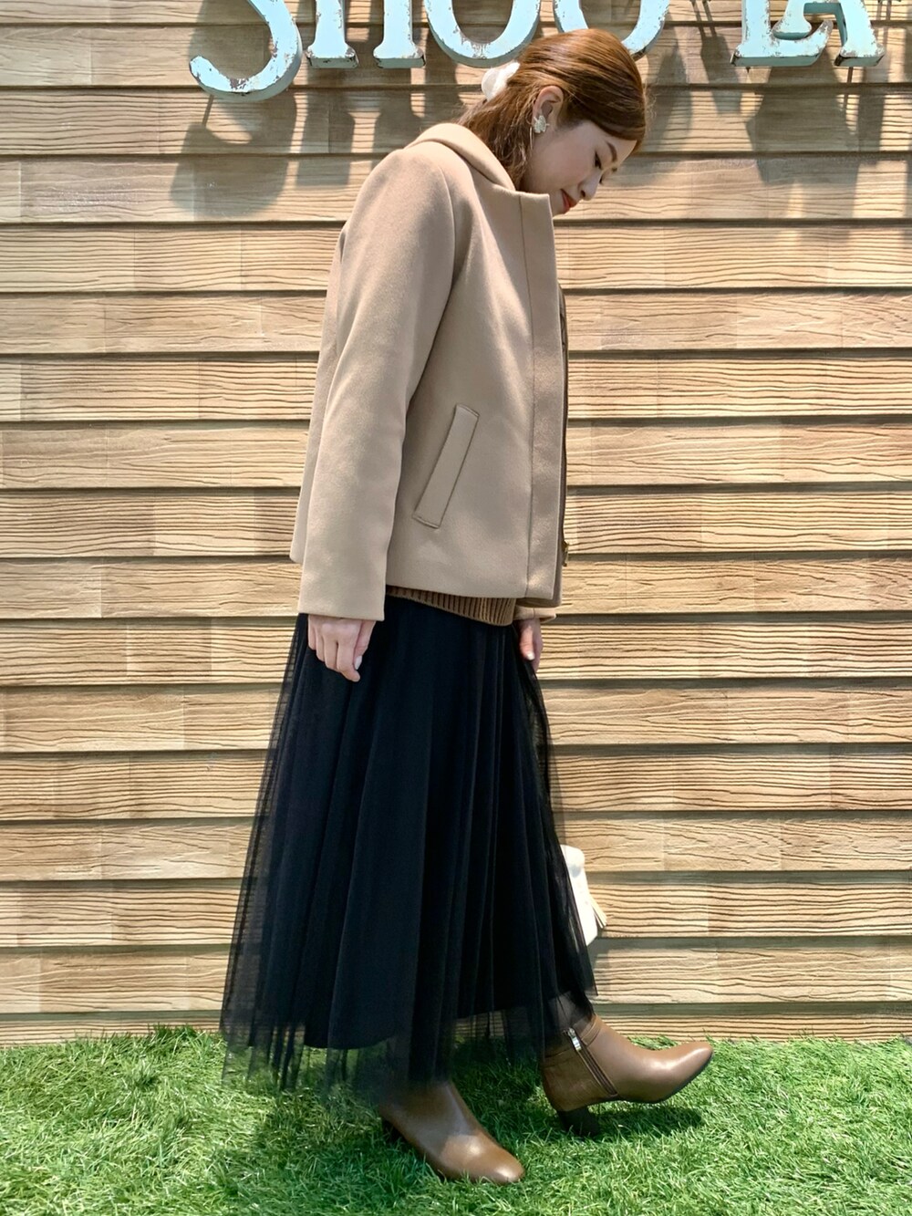 イエロー系のその他アウター、ブラウン系のニット/セーター、ブラック系のスカートを着用したレディースの冬コーディネートの2枚目の写真