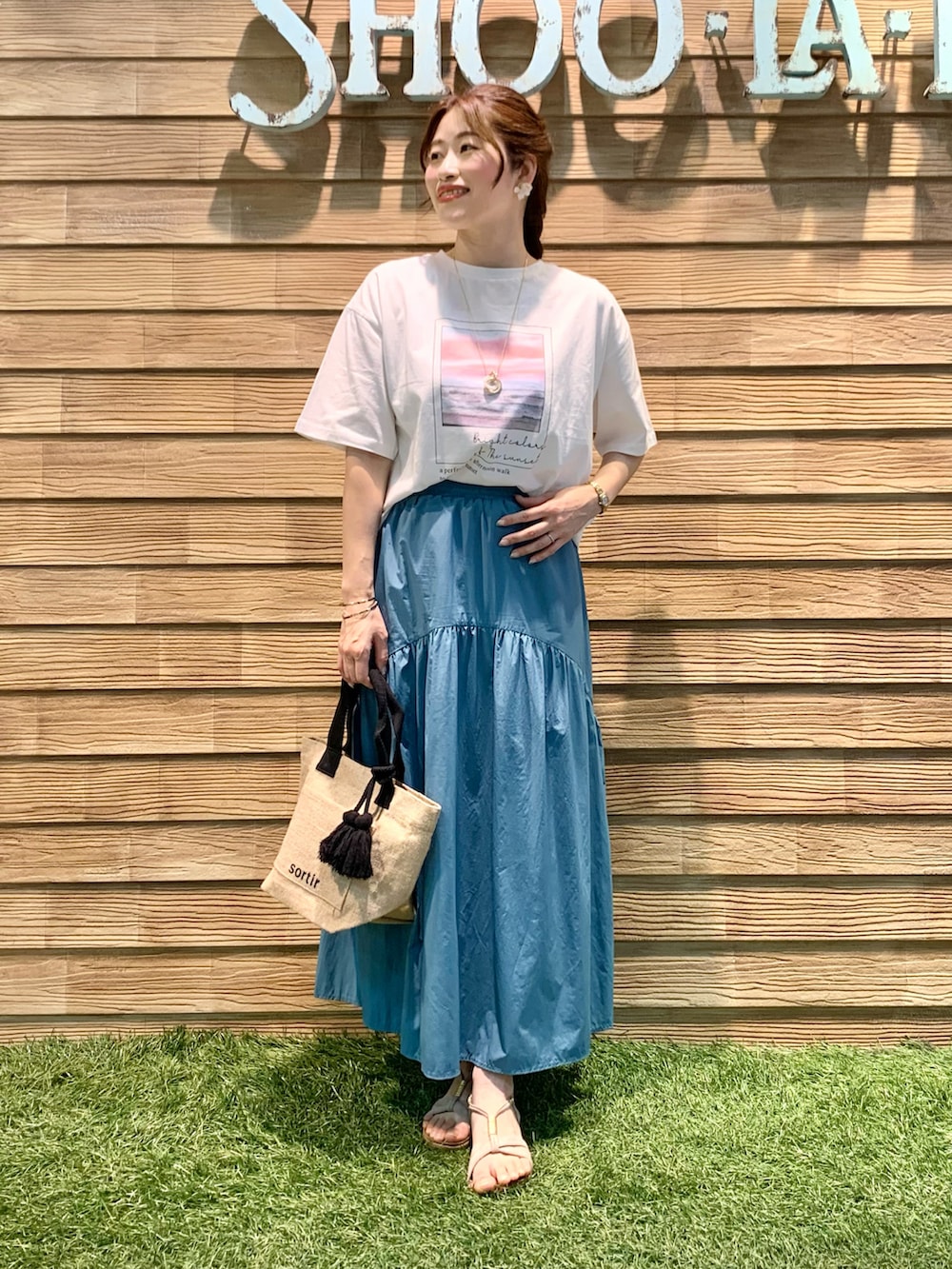 ホワイト系のTシャツ/カットソー、ブルー系のスカート、ブラック系のトートバッグを着用したレディースの秋コーディネートの2枚目の写真