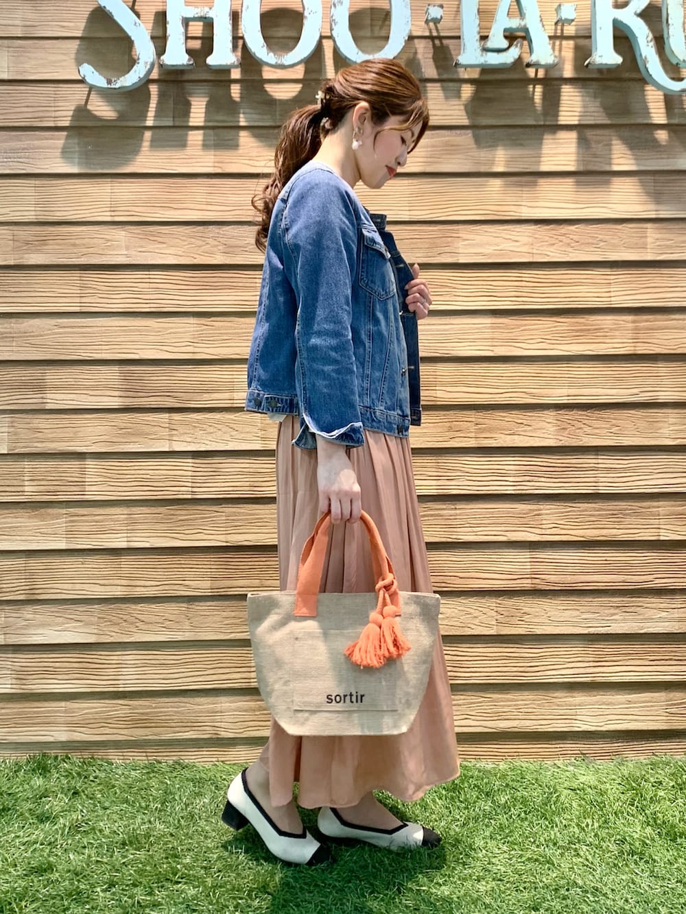 ブルー系のデニムジャケット、ベージュ系のTシャツ/カットソー、オレンジ系のスカートを着用したレディースの春コーディネートの4枚目の写真