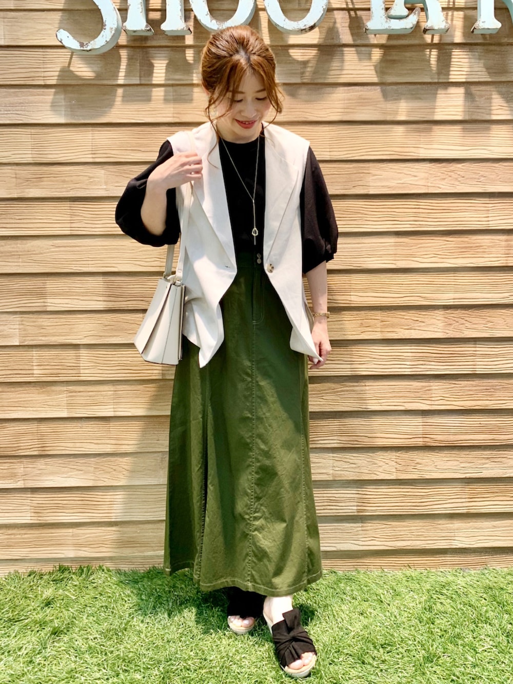 ベージュ系のベスト、ブラック系のTシャツ/カットソー、グリーン系のスカートを着用したレディースの夏コーディネートの2枚目の写真