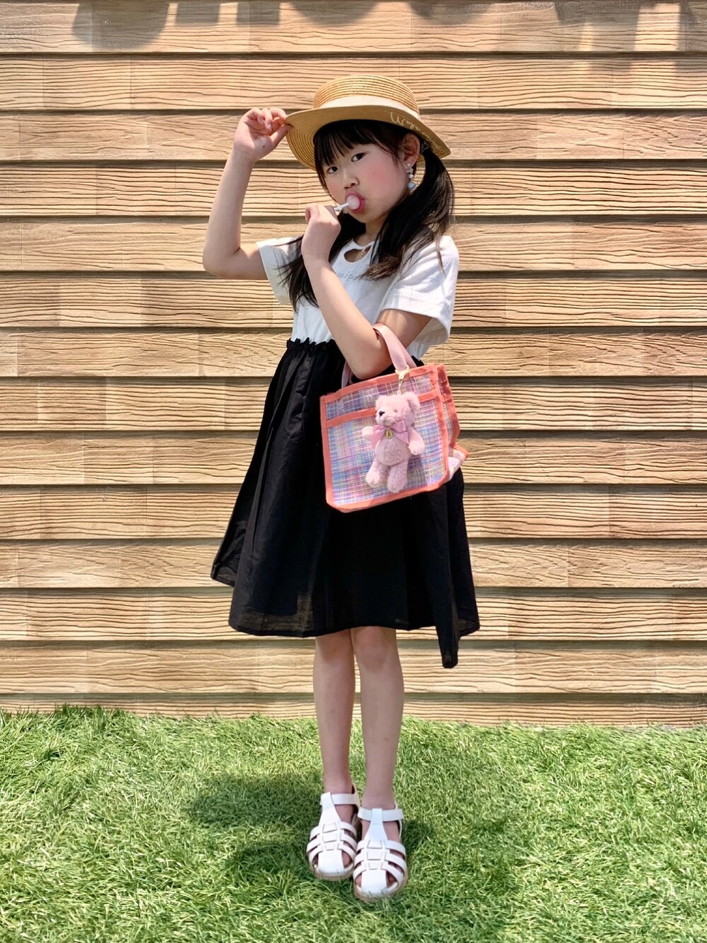 ブラック系のワンピース、ピンク系のトートバッグ、ベージュ系のハットを着用したキッズの秋コーディネートの2枚目の写真