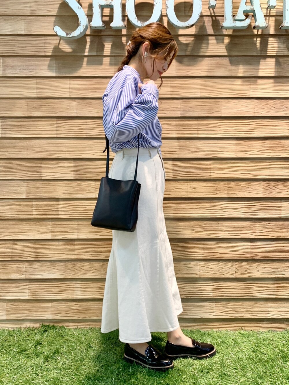 ブルー系のワンピース、ホワイト系のデニムスカート、ブラック系のショルダーバッグを着用したレディースの春コーディネートの4枚目の写真