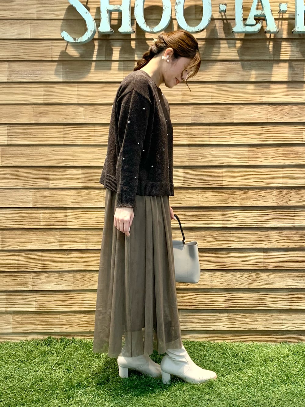 ブラウン系のニット/セーター、ブラウン系のスカート、ベージュ系のトートバッグを着用したレディースの冬コーディネートの4枚目の写真