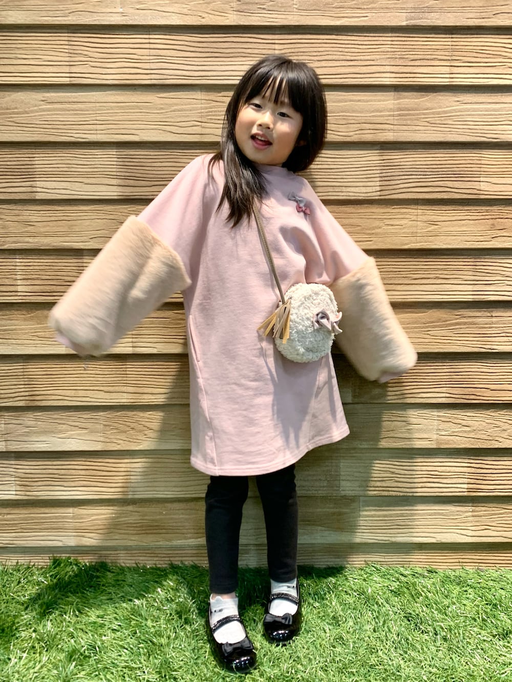 ピンク系のワンピース、ホワイト系のショルダーバッグ、ブラック系のドレスシューズを着用したキッズの冬コーディネートの5枚目の写真