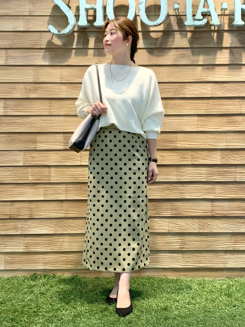 ホワイト系のニット/セーター、グリーン系のスカート、ブラック系のショルダーバッグを着用したレディースの春コーディネートの3枚目の写真