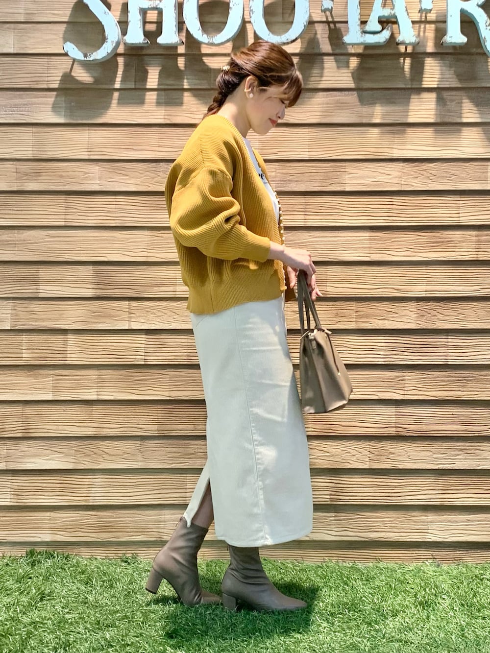 イエロー系のカーディガン/ボレロ、ホワイト系のTシャツ/カットソー、ホワイト系のスカートを着用したレディースの冬コーディネートの4枚目の写真