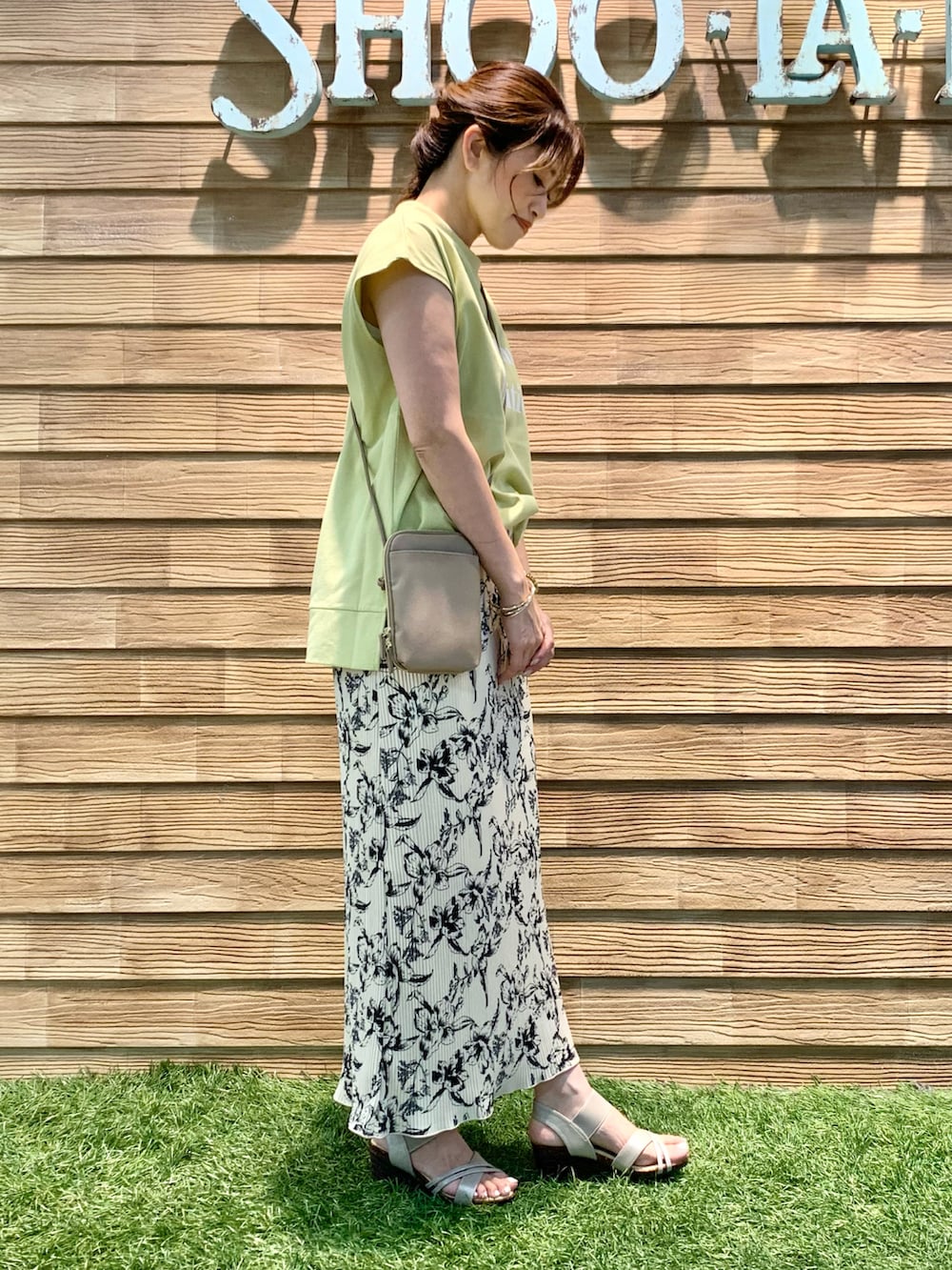 グリーン系のTシャツ/カットソー、ホワイト系のスカート、ベージュ系のショルダーバッグを着用したレディースの夏コーディネートの3枚目の写真