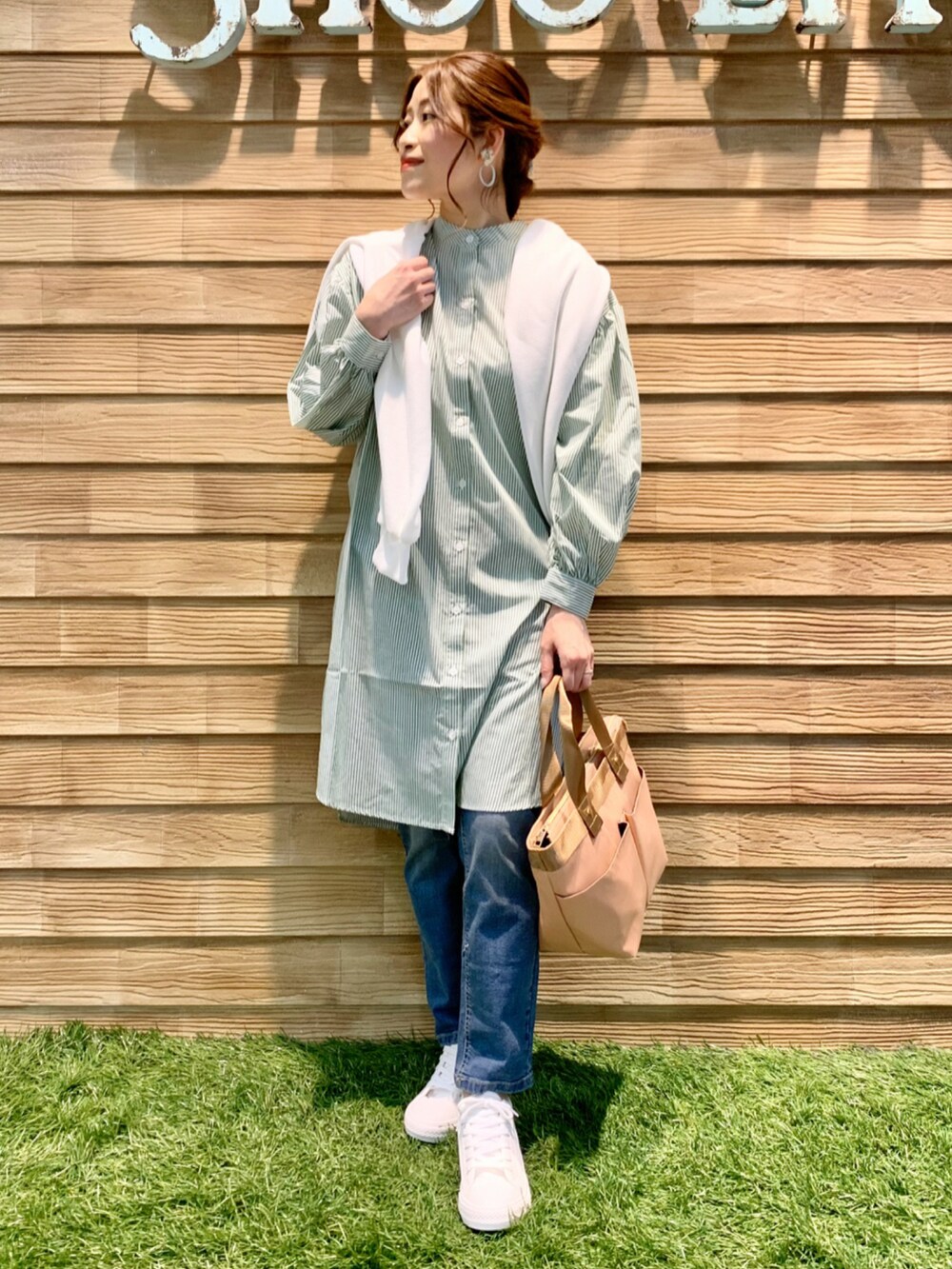 グリーン系のワンピース、ホワイト系のカーディガン/ボレロ、ブルー系のデニムパンツを着用したレディースの春コーディネートの2枚目の写真