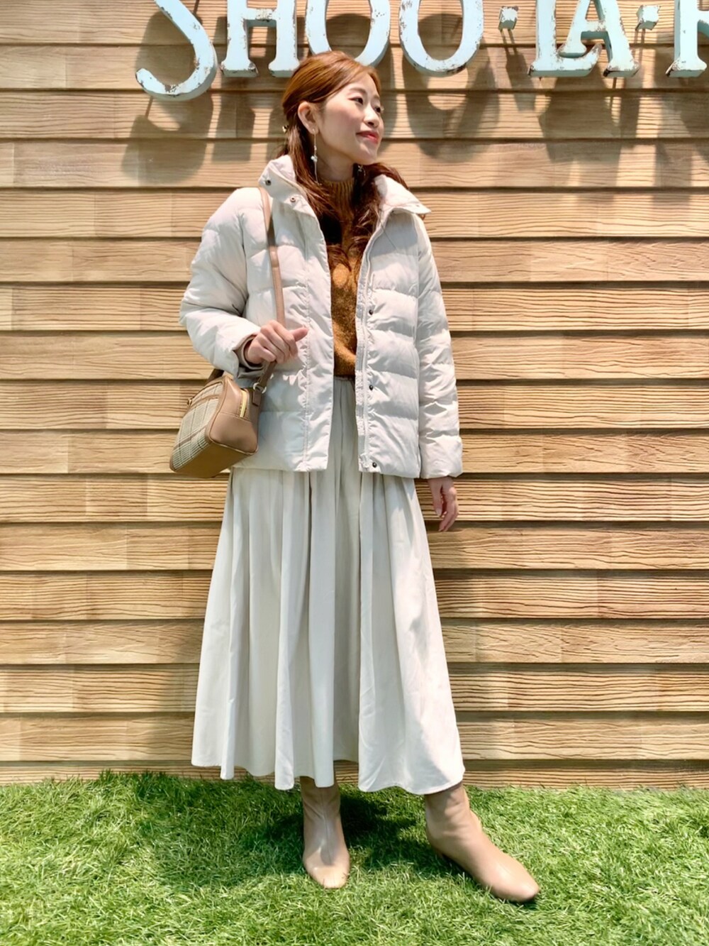 ホワイト系のダウンジャケット/コート、オレンジ系のニット/セーター、ホワイト系のスカートを着用したレディースの冬コーディネートの2枚目の写真