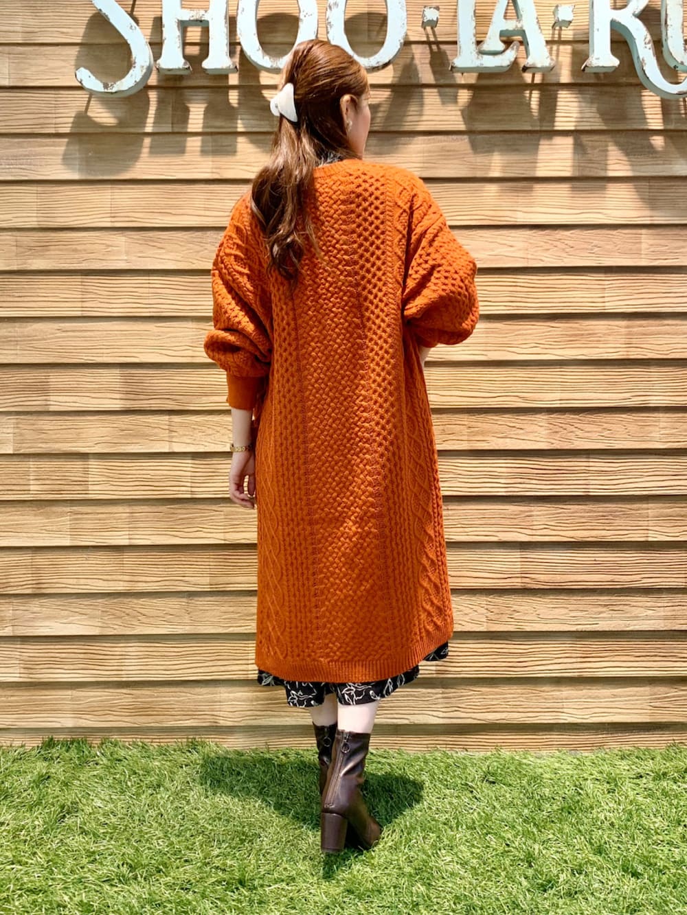 オレンジ系のカーディガン/ボレロ、ブラック系のワンピース、ブラウン系のブーツを着用したレディースの秋コーディネートの5枚目の写真