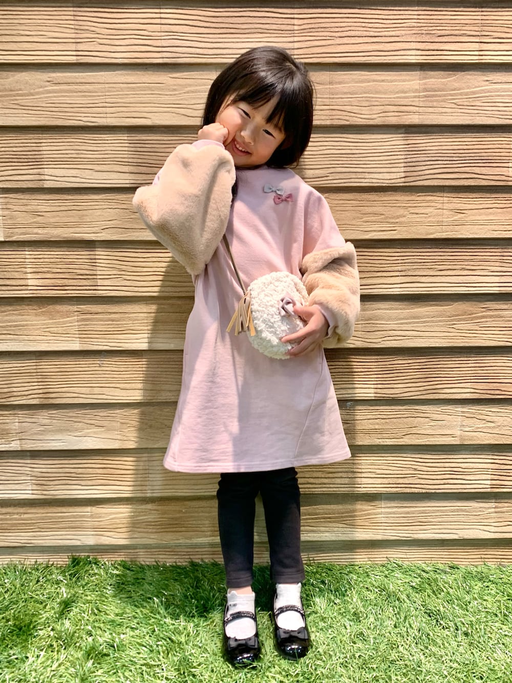 ピンク系のワンピース、ホワイト系のショルダーバッグ、ブラック系のドレスシューズを着用したキッズの冬コーディネートの2枚目の写真