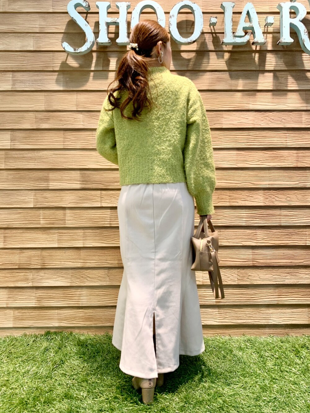 グリーン系のニット/セーター、ホワイト系のスカート、グレー系のショルダーバッグを着用したレディースの秋コーディネートの5枚目の写真