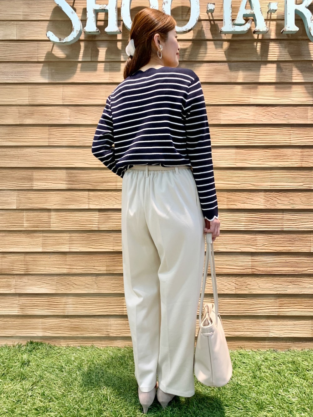 ブルー系のニット/セーター、ホワイト系のその他パンツ、ホワイト系のトートバッグを着用したレディースの春コーディネートの4枚目の写真