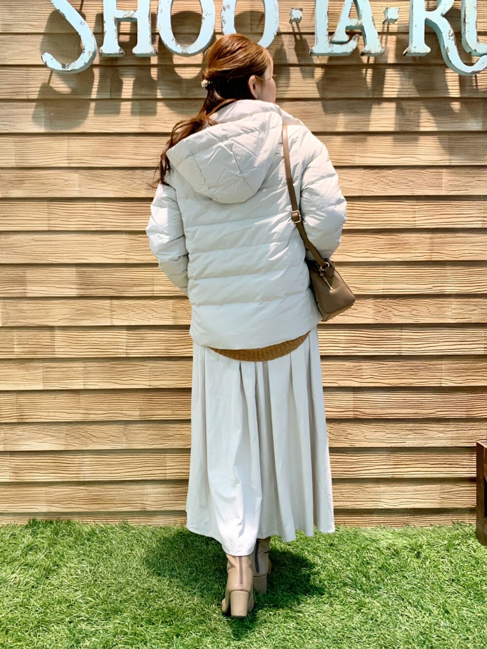 ホワイト系のダウンジャケット/コート、オレンジ系のニット/セーター、ホワイト系のスカートを着用したレディースの冬コーディネートの4枚目の写真