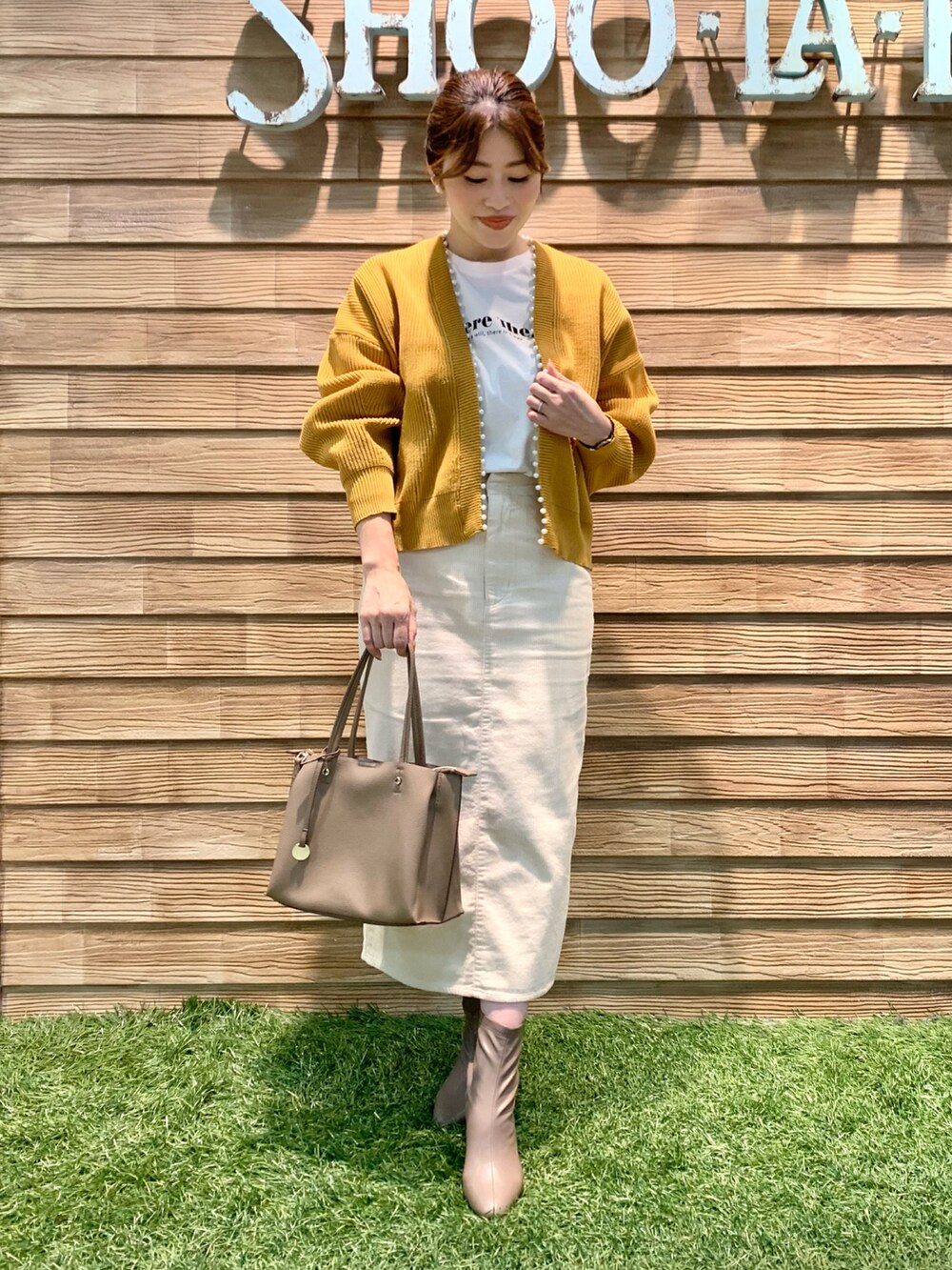 イエロー系のカーディガン/ボレロ、ホワイト系のTシャツ/カットソー、ホワイト系のスカートを着用したレディースの冬コーディネートの2枚目の写真