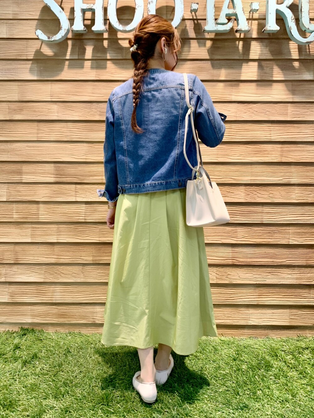 ブルー系のデニムジャケット、ホワイト系のニット/セーター、イエロー系のスカートを着用したレディースの春コーディネートの5枚目の写真