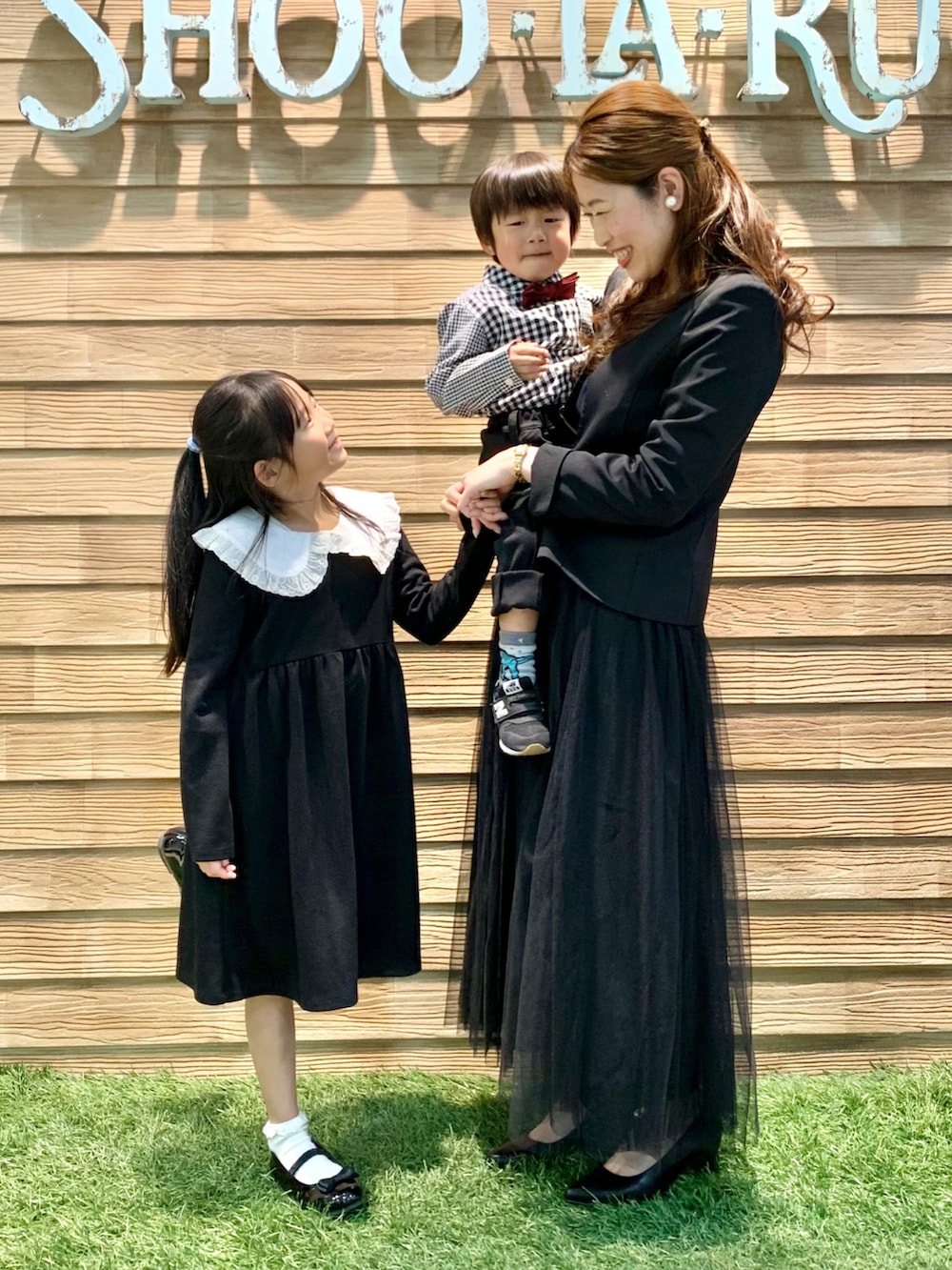 ブラック系のワンピース、ブラック系のドレスシューズ、ブラウン系のラッピングキットを着用したキッズの春コーディネートの4枚目の写真