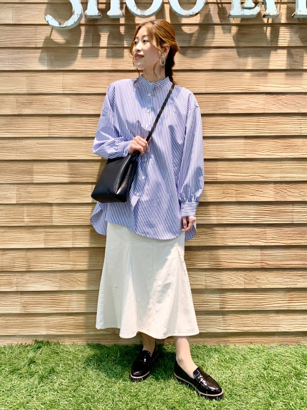 ブルー系のワンピース、ホワイト系のデニムスカート、ブラック系のショルダーバッグを着用したレディースの春コーディネートの3枚目の写真