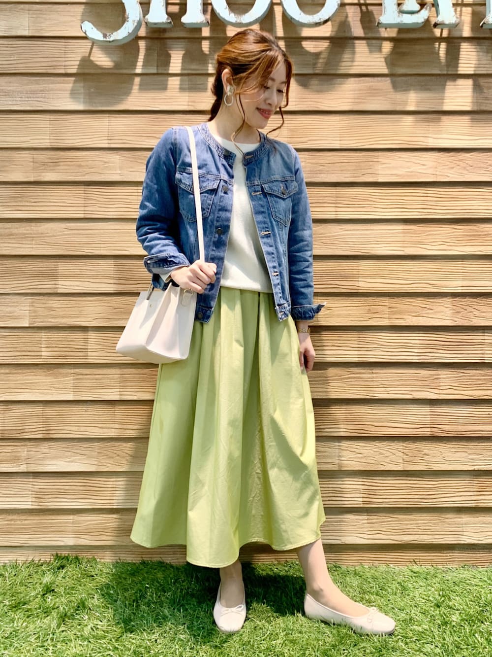ブルー系のデニムジャケット、ホワイト系のニット/セーター、イエロー系のスカートを着用したレディースの春コーディネートの2枚目の写真