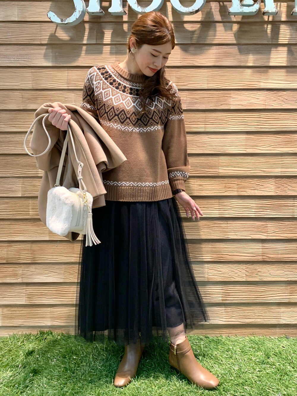 イエロー系のその他アウター、ブラウン系のニット/セーター、ブラック系のスカートを着用したレディースの冬コーディネートの3枚目の写真