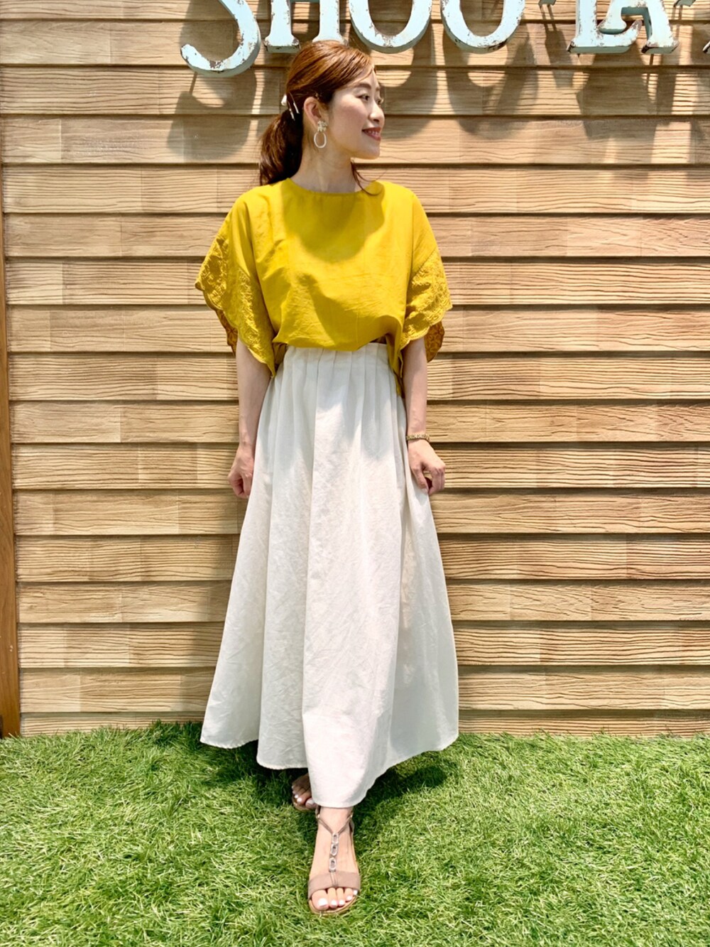 イエロー系のシャツ/ブラウス、ホワイト系のスカート、ベージュ系のサンダルを着用したレディースの夏コーディネートの4枚目の写真