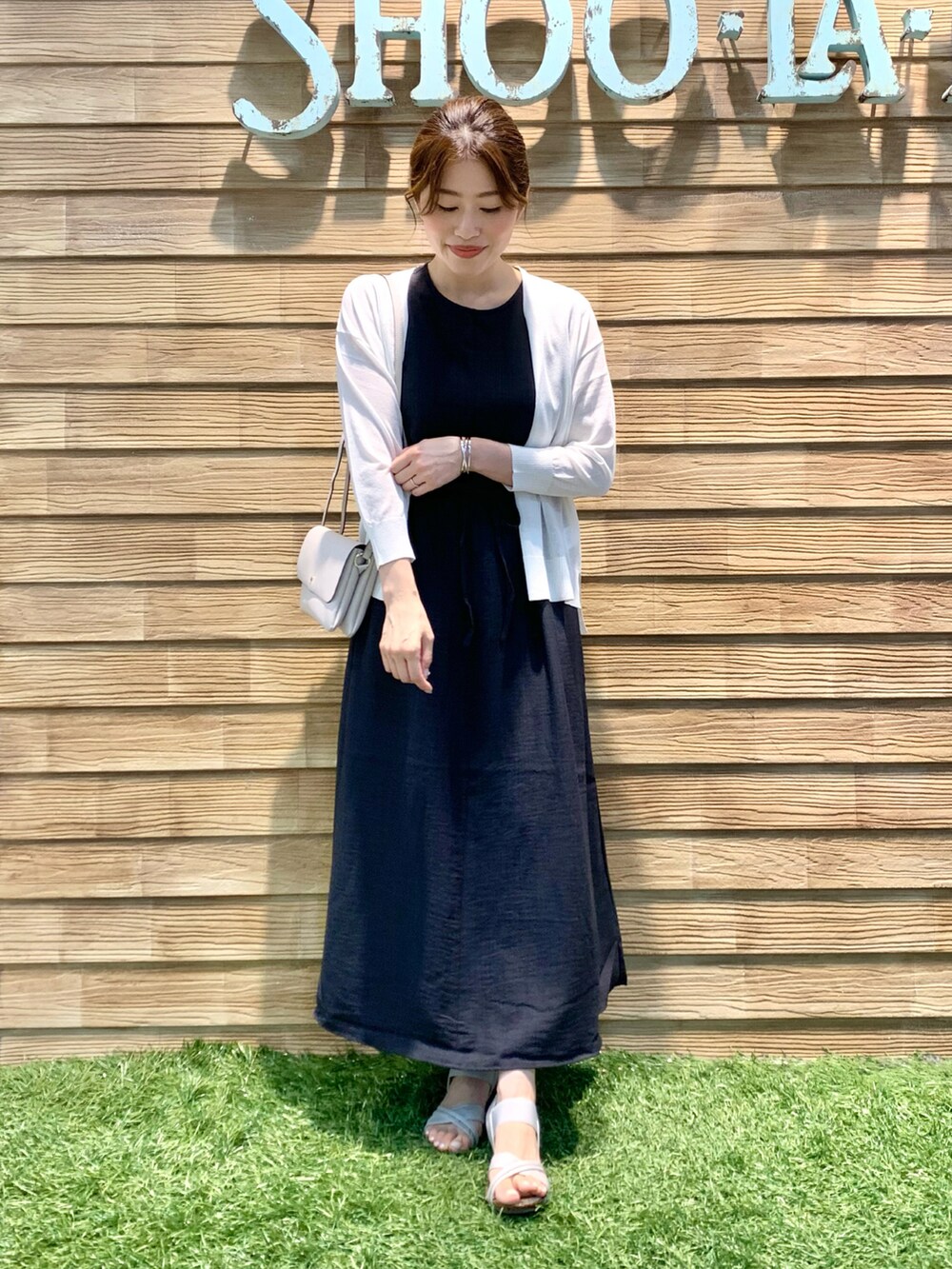 グレー系のワンピース、ホワイト系のカーディガン/ボレロ、グレー系のショルダーバッグを着用したレディースの秋コーディネートの2枚目の写真