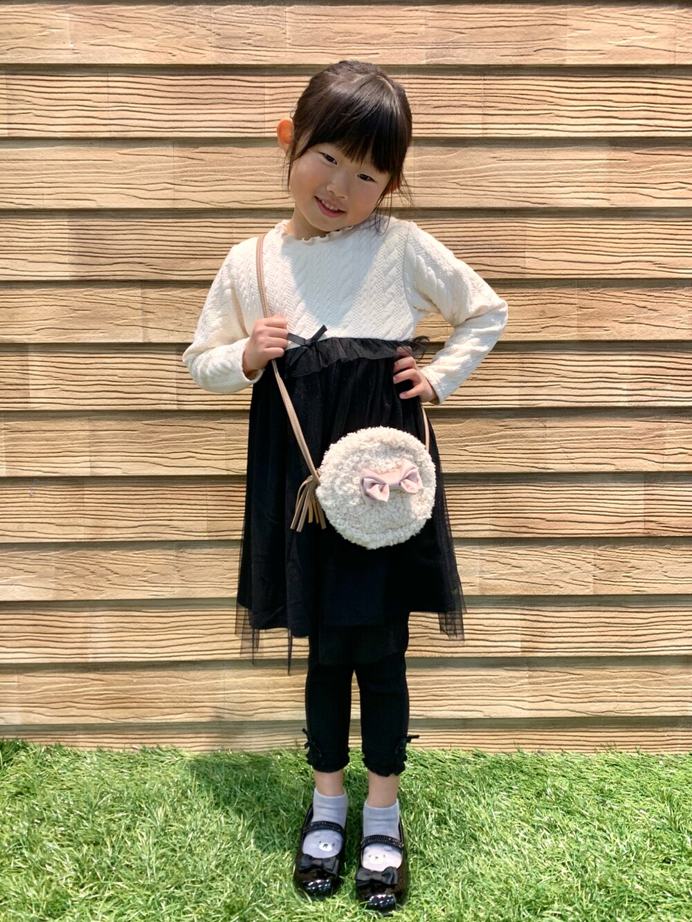 ピンク系のダウンジャケット/コート、ベージュ系のワンピース、ブラック系のその他パンツを着用したキッズの冬コーディネートの2枚目の写真