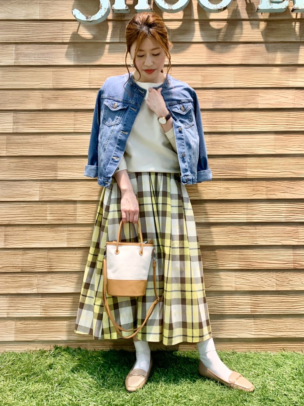 ブルー系のデニムジャケット、ホワイト系のニット/セーター、イエロー系のスカートを着用したレディースの春コーディネートの2枚目の写真