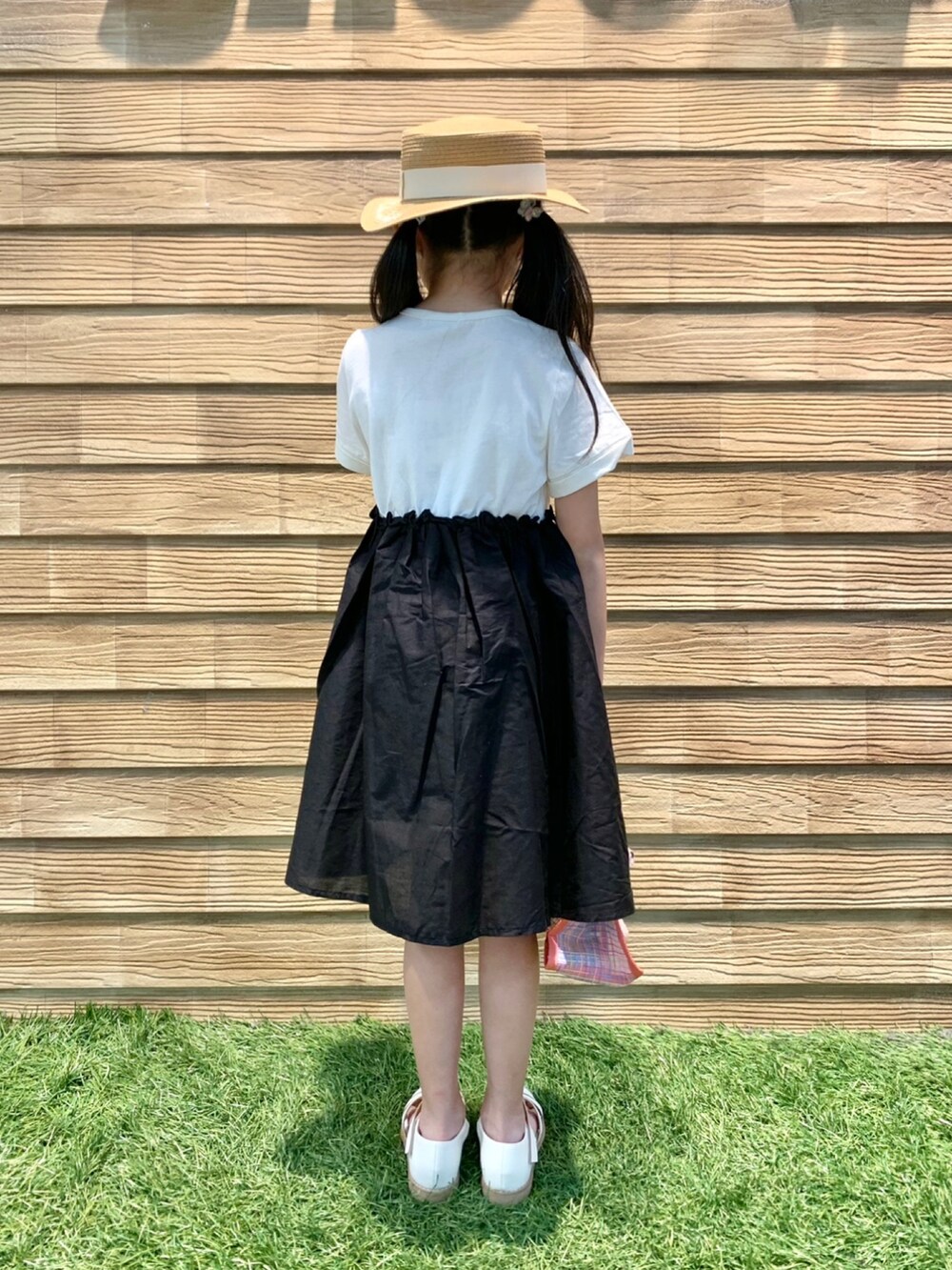 ブラック系のワンピース、ピンク系のトートバッグ、ベージュ系のハットを着用したキッズの秋コーディネートの4枚目の写真