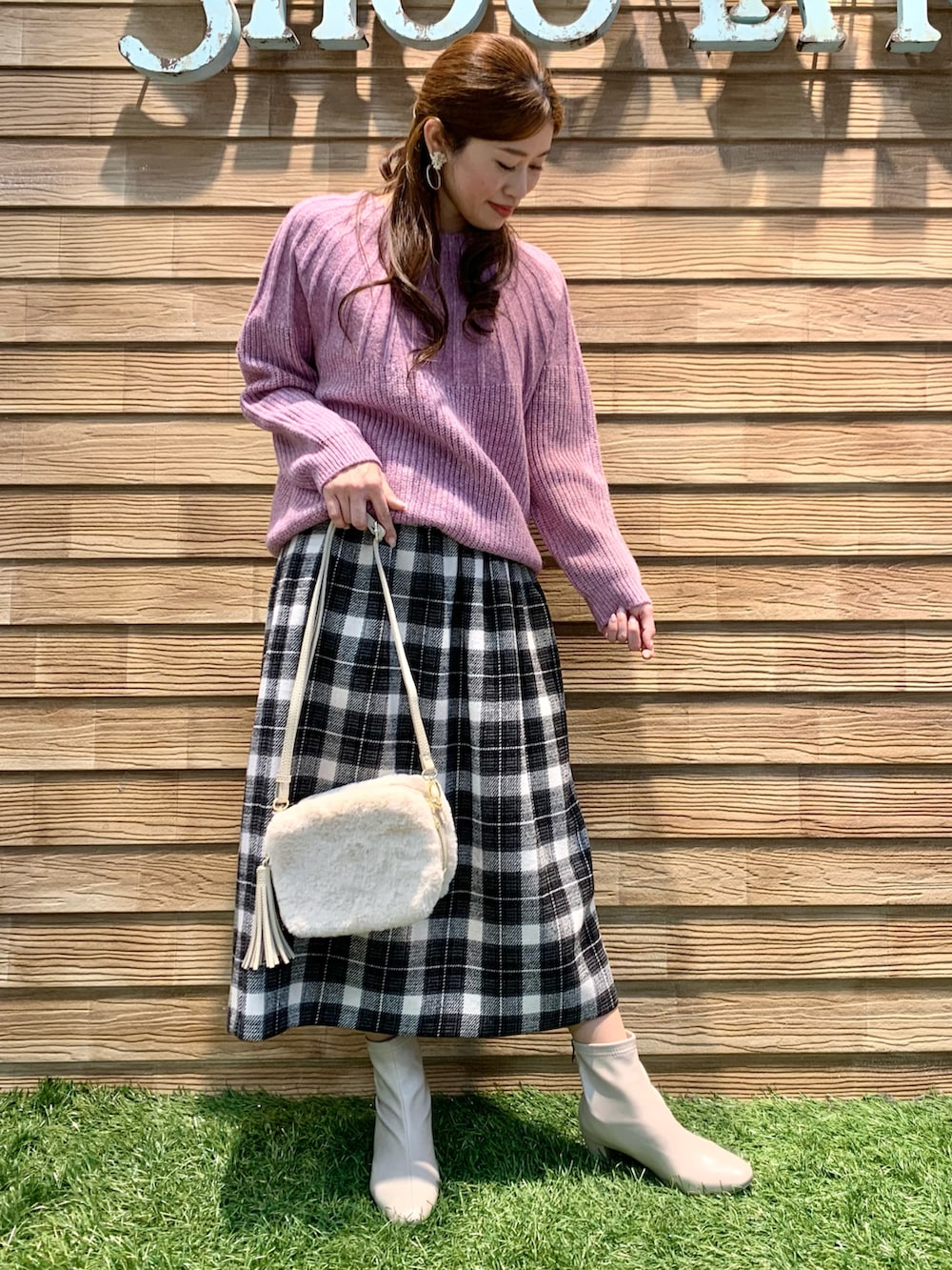 ピンク系のニット/セーター、グレー系のスカート、ホワイト系のショルダーバッグを着用したレディースの冬コーディネートの2枚目の写真