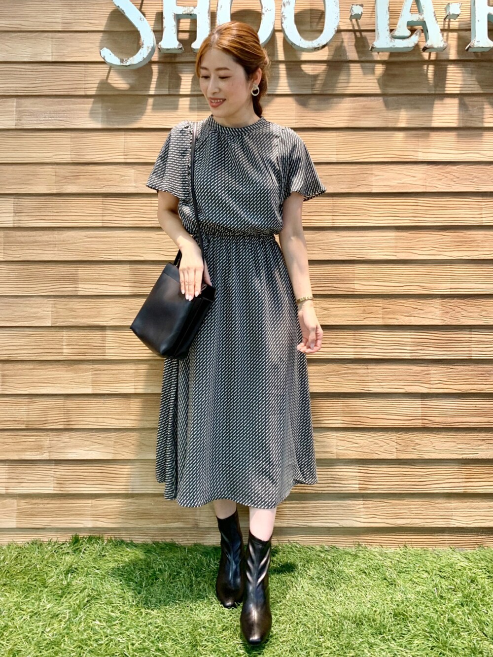 ブラック系のワンピース、ブラック系のショルダーバッグ、ブラック系のブーツを着用したレディースの秋コーディネートの3枚目の写真