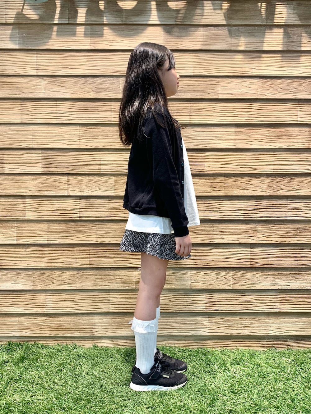 ブラック系のカーディガン/ボレロ、ホワイト系のTシャツ/カットソー、ブラック系のスカートを着用したキッズの春コーディネートの4枚目の写真