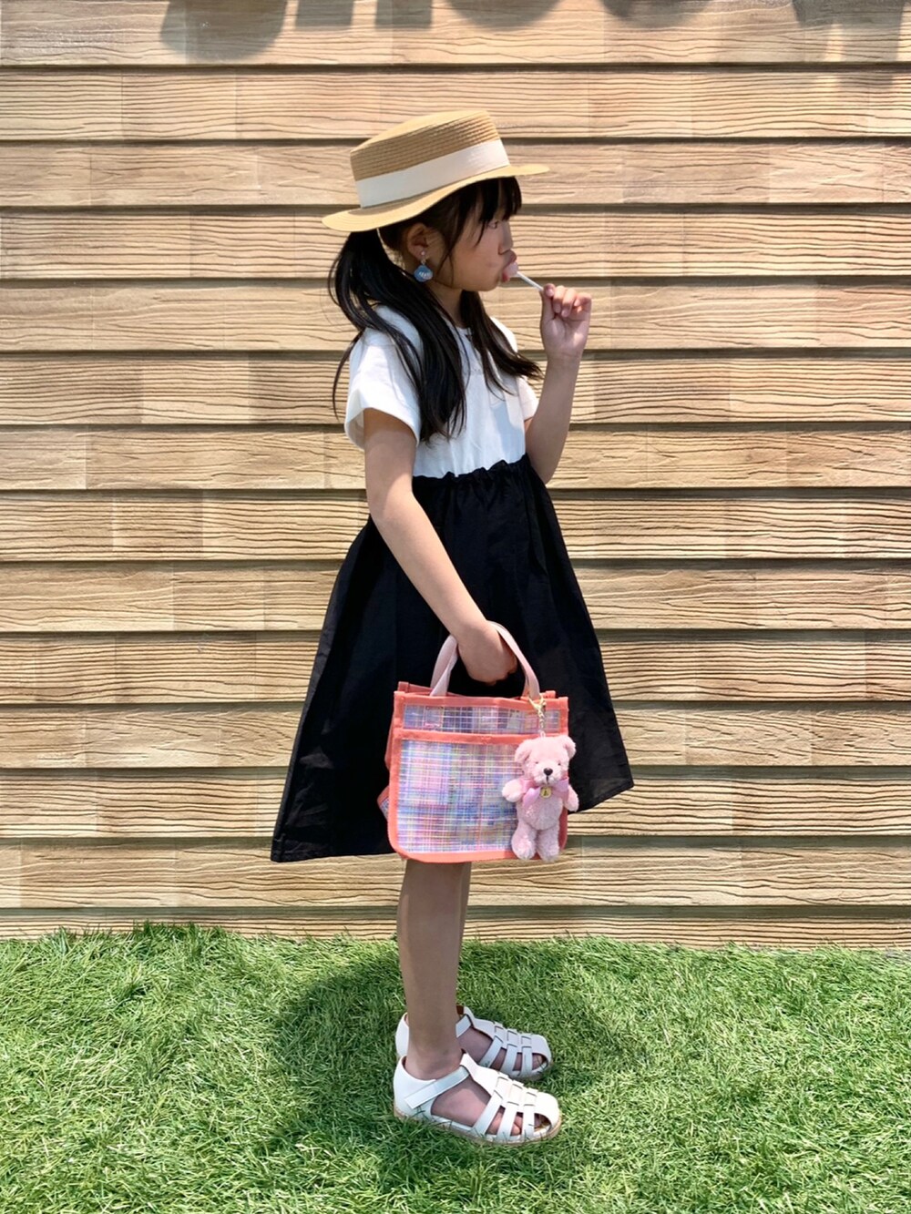 ブラック系のワンピース、ピンク系のトートバッグ、ベージュ系のハットを着用したキッズの秋コーディネートの3枚目の写真