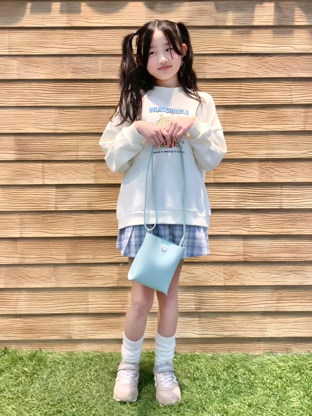 ホワイト系のスウェット、ブルー系のスカート、グリーン系のショルダーバッグを着用したキッズの夏コーディネートの2枚目の写真