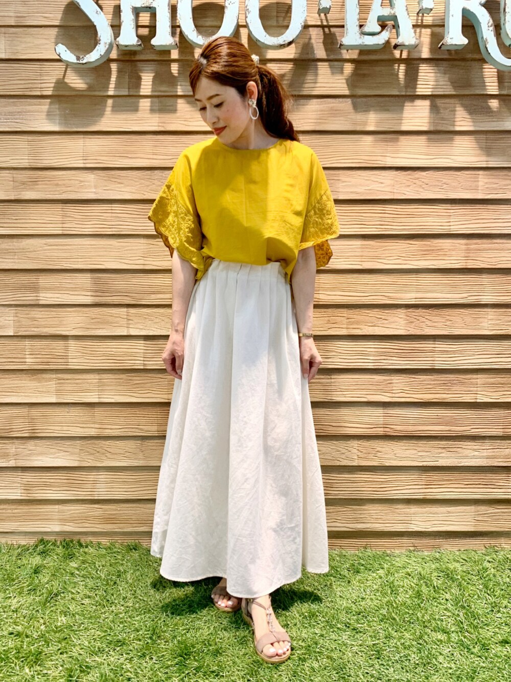 イエロー系のシャツ/ブラウス、ホワイト系のスカート、ベージュ系のサンダルを着用したレディースの夏コーディネートの2枚目の写真