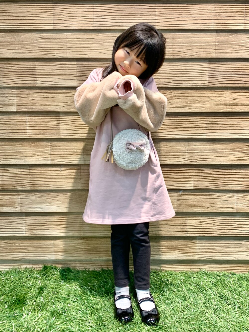 ピンク系のワンピース、ホワイト系のショルダーバッグ、ブラック系のドレスシューズを着用したキッズの冬コーディネートの4枚目の写真
